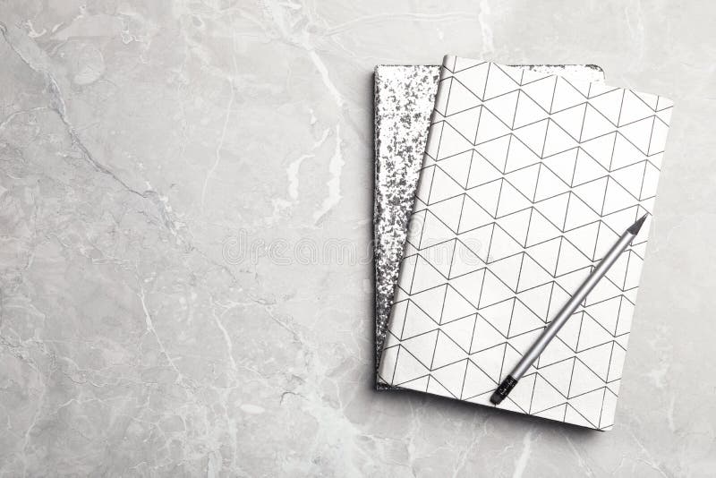 Stylish notebooks and pencil on marble table, top view. Space for text royalty free stock photo