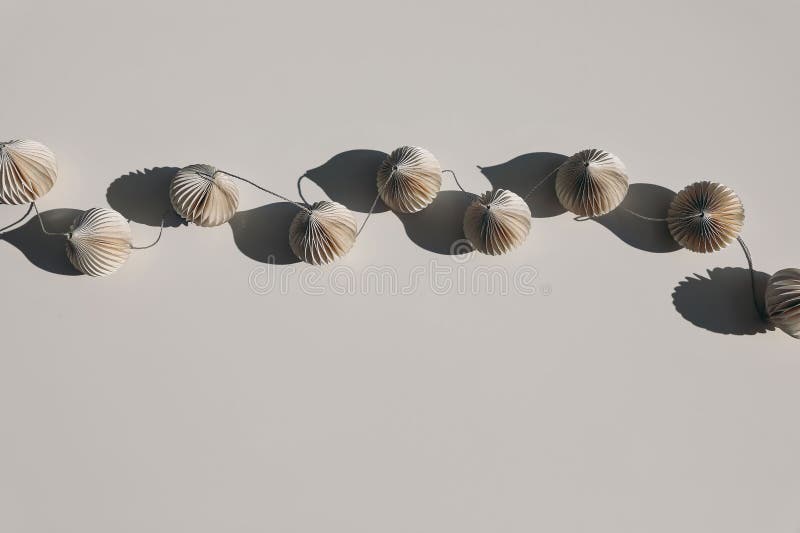 Stylish paper christmas ornamets balls garland on beige table background in sunlight, long shadows. Minimal boho royalty free stock images