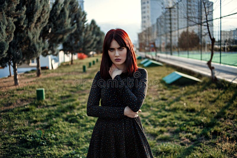 Stylish portrait of a beautiful woman in a black dress at sunset