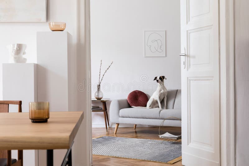 Stylish scandinavian interior of living room with design wooden table, chairs, grey sofa, decoration, personal accessories.