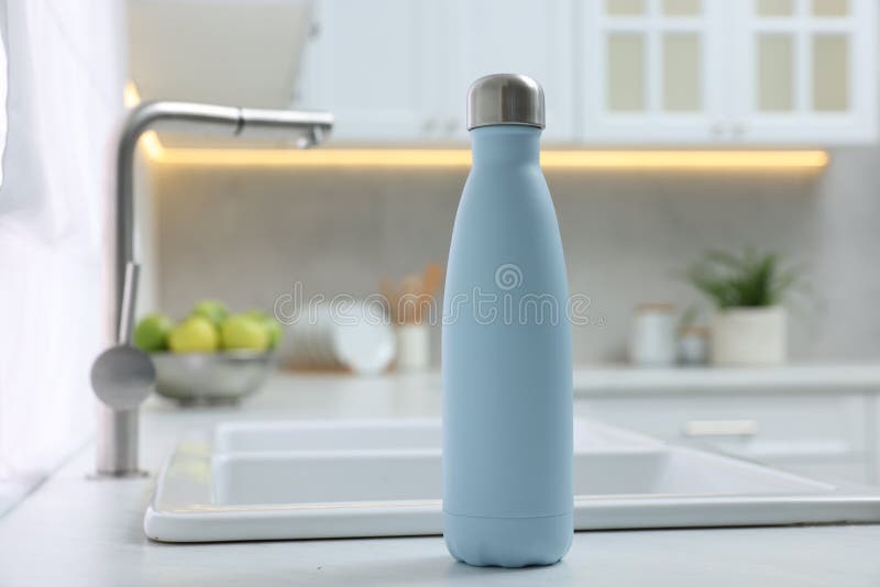 Stylish Thermo Bottle on White Countertop in Kitchen. Space for Text