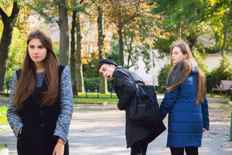 Stylish unfaithful young male ugly staring at fashionable girl and make jealous his girlfriend who just walked by them. royalty free stock images Stylish unfaithful young male ugly staring at fashionable girl and make jealous his girlfriend who just walked by them. royalty free stock images