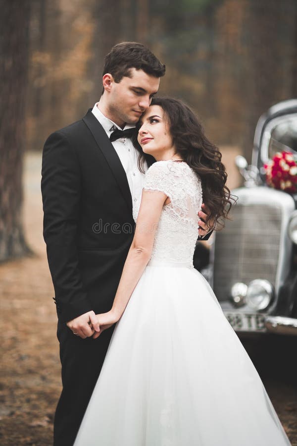 Stylish wedding couple, bride, groom kissing and hugging near retro car in autumn stock photography Stylish wedding couple, bride, groom kissing and hugging near retro car in autumn stock photography