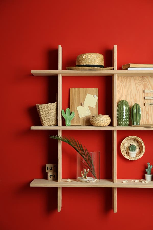 Stylish Wooden Shelves with Decorative Elements on Red Wall Stock Image