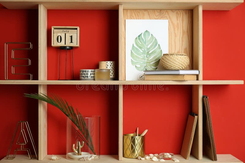 Stylish Wooden Shelves with Decorative Elements on Red Wall Stock Photo