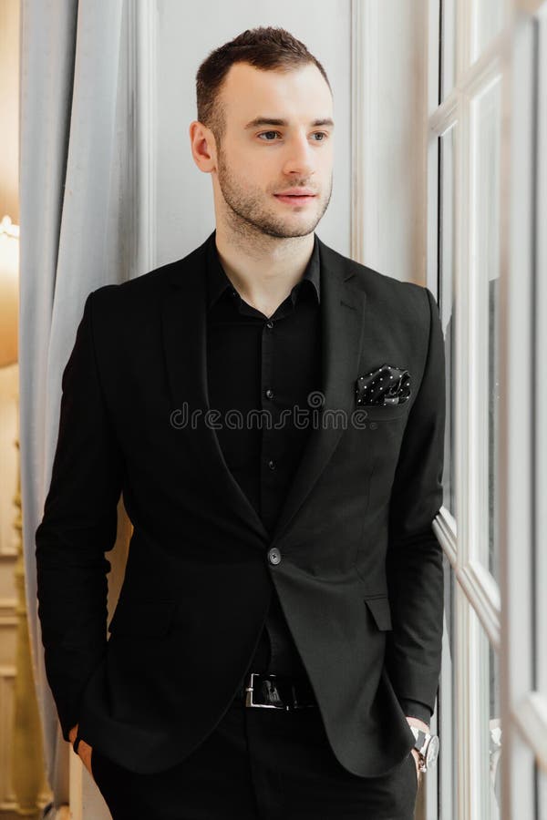 Stylish young bristle man is standing near the big vintage window and looking far away. royalty free stock photo Stylish young bristle man is standing near the big vintage window and looking far away. royalty free stock photo
