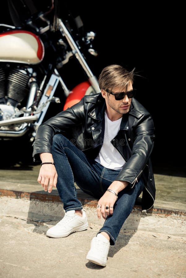 Stylish Young Man in Leather Jacket and Sunglasses Sitting on Concrete ...
