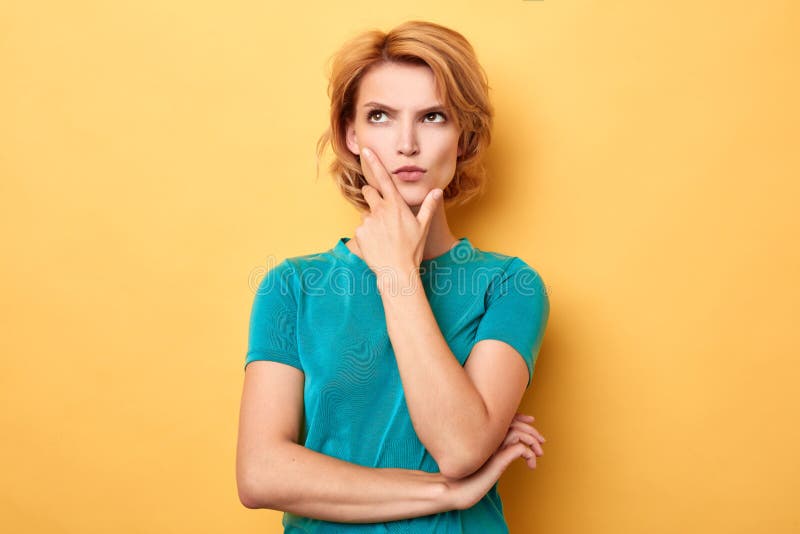 Stylish young puzzled woman touching her chin looking up stock image Stylish young puzzled woman touching her chin looking up stock image