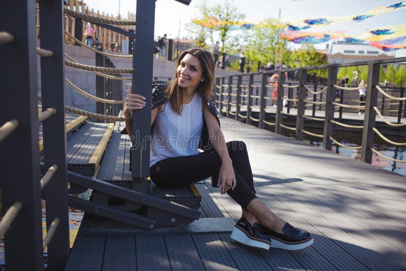 Stylish young woman on summer city walk, sitting on the stairs