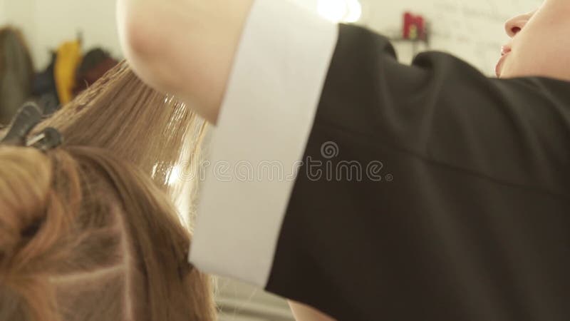 Styliste en coiffure peignant les cheveux femelles et coupant avec des ciseaux de coiffure dans le salon de beauté Fermez-vous ve banque de vidéos