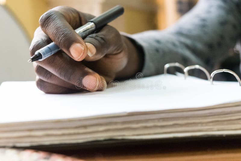 Stylo de participation africain d'homme à disposition à écrire sur le livre blanc vide images libres de droits Stylo de participation africain d'homme à disposition à écrire sur le livre blanc vide images libres de droits