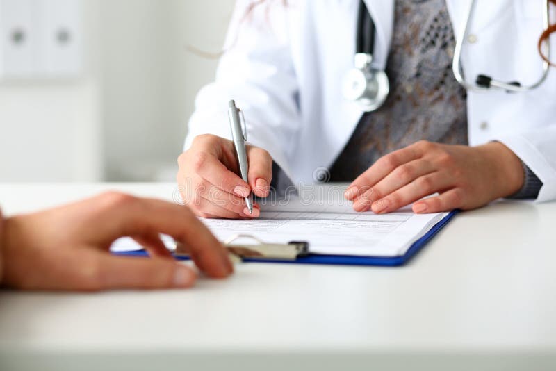 Stylo femelle d'argent de prise de main de docteur remplissant liste d'histoire patiente photographie stock libre de droits Stylo femelle d'argent de prise de main de docteur remplissant liste d'histoire patiente photographie stock libre de droits
