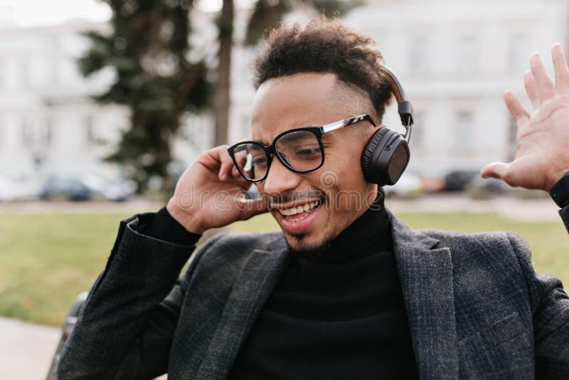 Städa upp porträtt av afrikansk kille på gott humör och njuta av favoritmusik. utomhusfoto av glad svart man med hårstrå royaltyfria bilder
