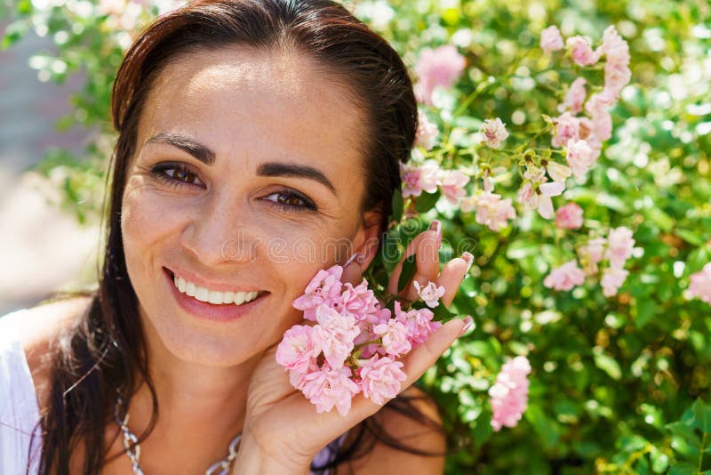 Städa upp porträtt vacker kvinna i parken med blommande små rosor. royaltyfri foto