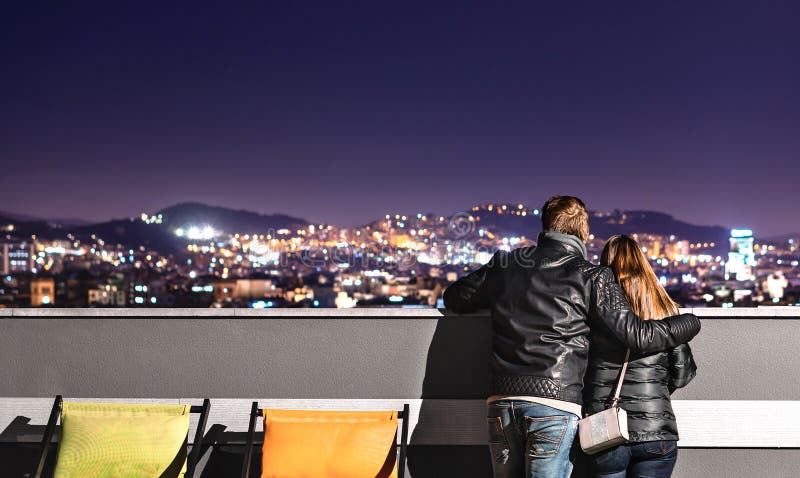 Städtische Paare, welche die Stadtansicht von der Dachspitze betrachten Freundholdingarm um seine Freundin Romantischer Abend für stockbild Städtische Paare, welche die Stadtansicht von der Dachspitze betrachten Freundholdingarm um seine Freundin Romantischer Abend für stockbild