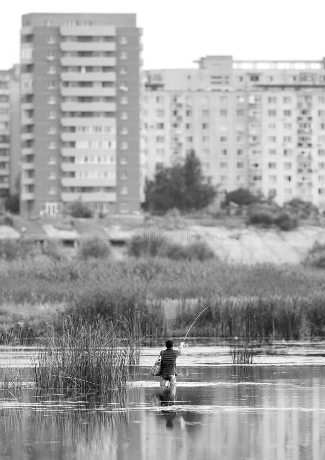 Unknown man fishing in the Vacaresti Lake, also as the Delta of Bucharest. Vacaresti lake is a strange, intriguing raw nature island between communist blocks of flats in a southern district of Bucharest, covering around 200 hectares, including some 80 hectares of water; a stable ecosystem consisting of fish, wild ducks, swans, lizards and gulls where during the summer nest over 90 species of wild birds. Unknown man fishing in the Vacaresti Lake, also as the Delta of Bucharest. Vacaresti lake is a strange, intriguing raw nature island between communist blocks of flats in a southern district of Bucharest, covering around 200 hectares, including some 80 hectares of water; a stable ecosystem consisting of fish, wild ducks, swans, lizards and gulls where during the summer nest over 90 species of wild birds.