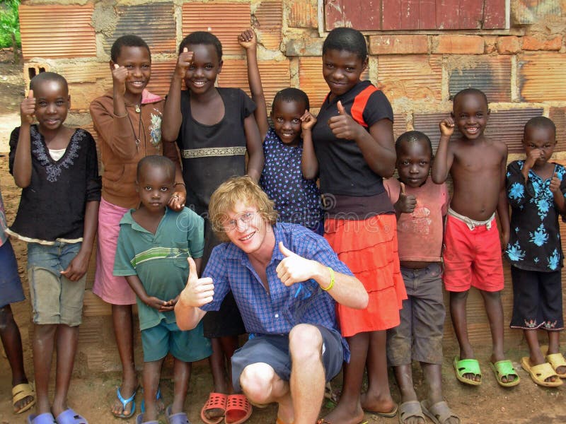 A young volunteer aid relief worker in Uganda, Africa taking some time out and having fun teaching some African children the thumbs up happy sign. Nothing beats the smiles from these children , they just light up over such simple things and are an absolute joy to be around. This photograph was taken in Kampala, Uganda, Africa while on the ground doing two months aid and relief work there and in the remote northern villages. This photograph is for editorial content only. A young volunteer aid relief worker in Uganda, Africa taking some time out and having fun teaching some African children the thumbs up happy sign. Nothing beats the smiles from these children , they just light up over such simple things and are an absolute joy to be around. This photograph was taken in Kampala, Uganda, Africa while on the ground doing two months aid and relief work there and in the remote northern villages. This photograph is for editorial content only.