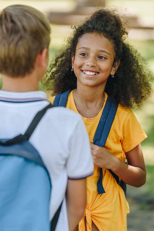 Ställande skolpojke nära smiling african american schoolgirl royaltyfri fotografi