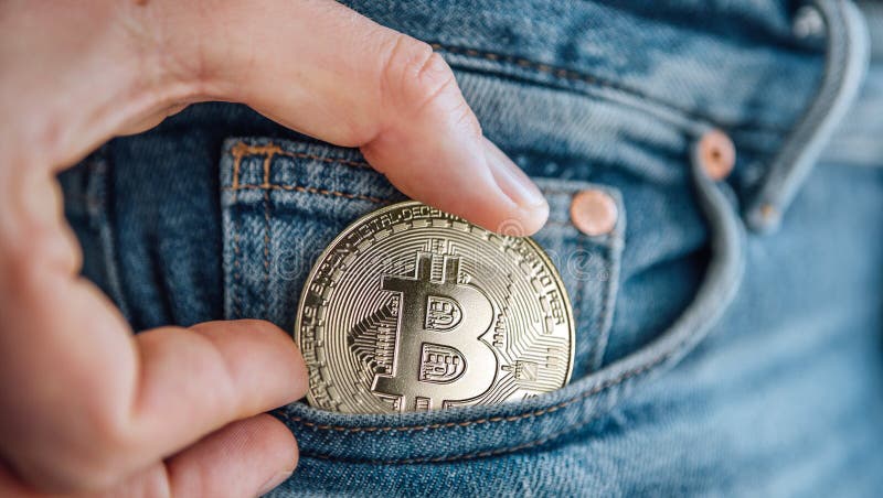 Stäng bilderna av fingrar som placerar bitmyntet i den blå jeans lilla ficka. spara digital valuta royaltyfri foto