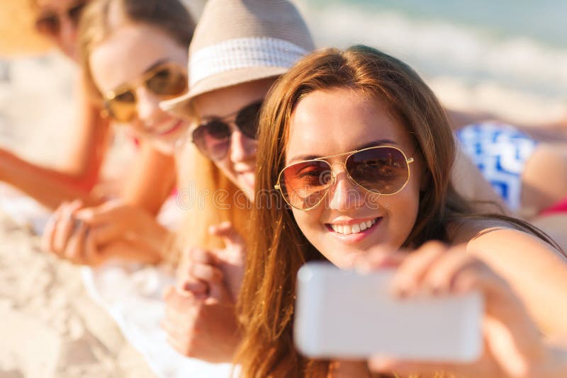 Stäng sig upp av att le kvinnor med smartphonen på stranden royaltyfria bilder Stäng sig upp av att le kvinnor med smartphonen på stranden royaltyfria bilder