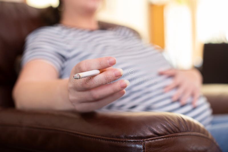 Stäng sig upp av den hemmastadda röka cigaretten för gravida kvinnan royaltyfri fotografi Stäng sig upp av den hemmastadda röka cigaretten för gravida kvinnan royaltyfri fotografi