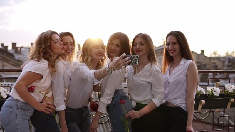 Stäng sig upp av förföriska unga kvinnor som utomhus tar selfie på en terrass Lyckliga gladlynta flickor i vit tillfällig kläder