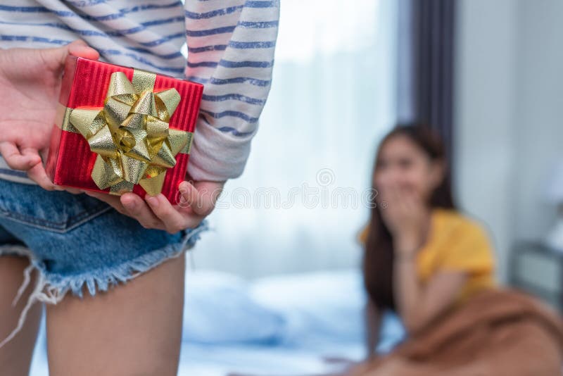 Stäng sig upp av kvinnahänder som rymmer gåvan för överraskning hennes flickvän arkivfoton Stäng sig upp av kvinnahänder som rymmer gåvan för överraskning hennes flickvän arkivfoton