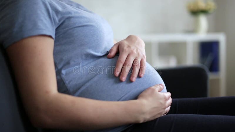 Stäng sig upp av lyckligt gravid kvinnasammanträde och att trycka på hennes mage arkivfilmer