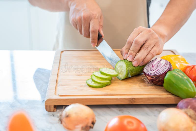 Stäng sig upp av manhanden som lagar mat och skivar grönsaken i kitchen