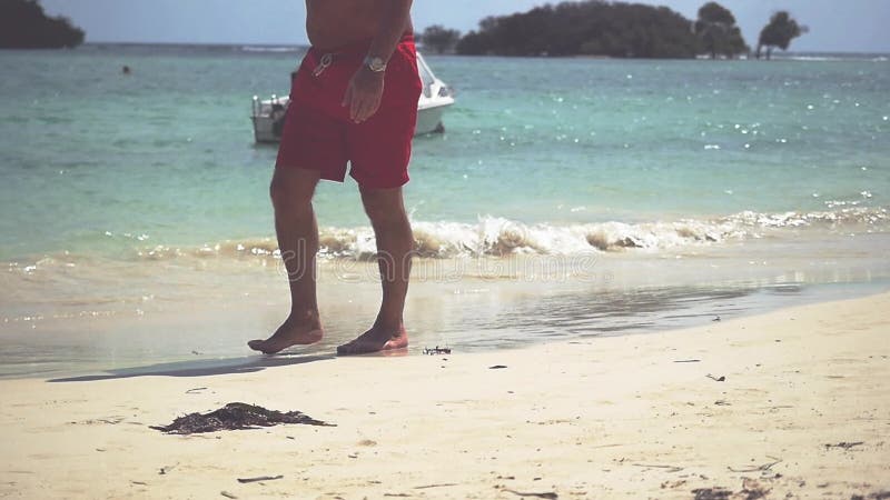 Stäng sig upp av manlig fot som går på guld- sand på stranden med havvågor Ferie för sommarsemester långsam rörelse