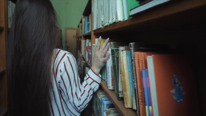 Stäng sig upp av smart se för händer och härlig ung flicka i den vita skjortan och exponeringsglas, i att välja för collageskolaa arkivfilmer