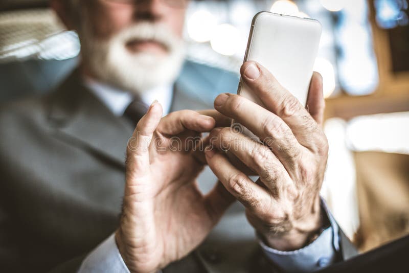 Stäng sig upp bild av den höga affärsmannen genom att använda mobiltelefonen fotografering för bildbyråer Stäng sig upp bild av den höga affärsmannen genom att använda mobiltelefonen fotografering för bildbyråer