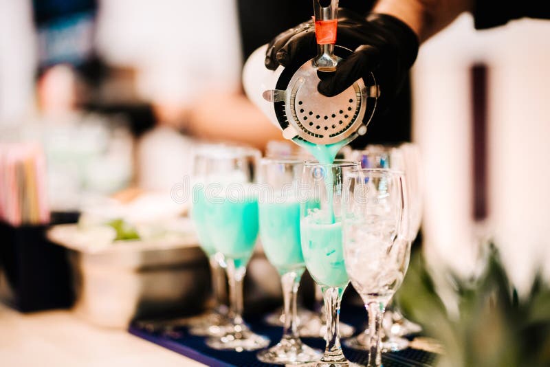 Stäng sig upp detaljer av den bartenderhjälpmedel och handen, medan hälla den exotiska tropiska blåa curacao coctailen in i expon