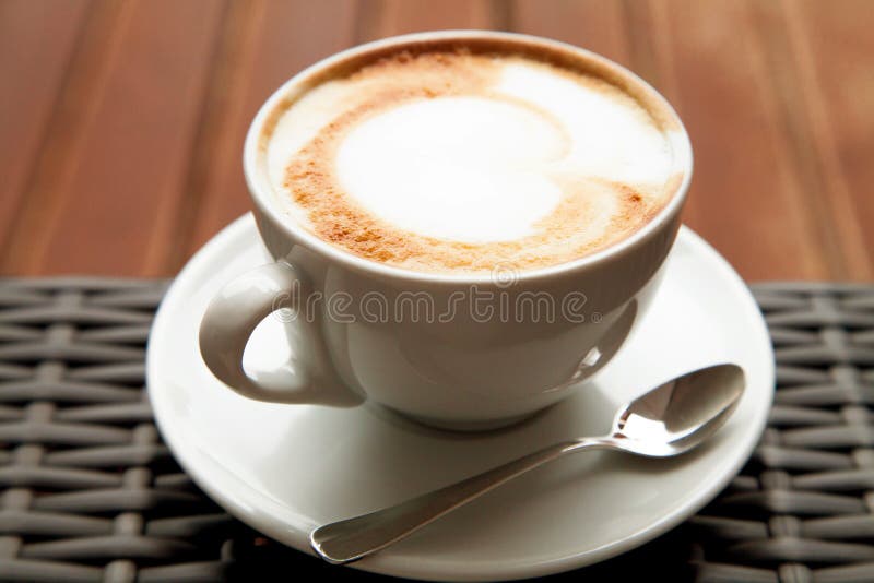 Stäng sig upp koppen av kaffe för hjärta för capuccinolattekonst på den wood backgrouen fotografering för bildbyråer