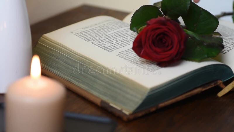 Stäng sig upp val upp av en röd ros från tabellen med boken och stearinljus