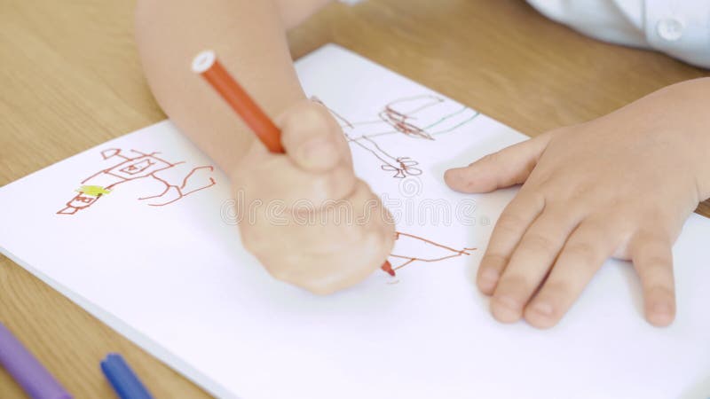 Stäng upp barnets händer och rita filtpennan på papper Barns kreativitet