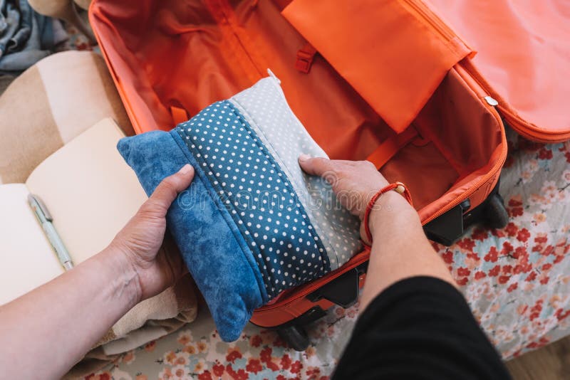 close-up shot of packing a suitcase for a summer holiday. a woman& x27;s hands organising a suitcase natural light, interior of a bedroom. close-up shot of packing a suitcase for a summer holiday. a woman& x27;s hands organising a suitcase natural light, interior of a bedroom.