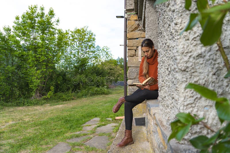 Close-up of a woman sitting reading at the entrance of a country house, concentrated. Close-up of a woman sitting reading at the entrance of a country house, concentrated