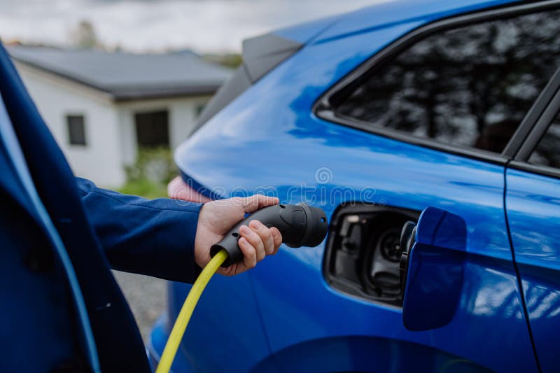 Close-up of electric car charging near a family house. Close-up of electric car charging near a family house.