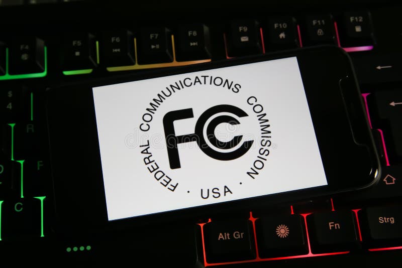 Viersen, Germany - March 9. 2022: Closeup of mobile phone screen with logo lettering of us federal communications commission on computer keyboard. Viersen, Germany - March 9. 2022: Closeup of mobile phone screen with logo lettering of us federal communications commission on computer keyboard