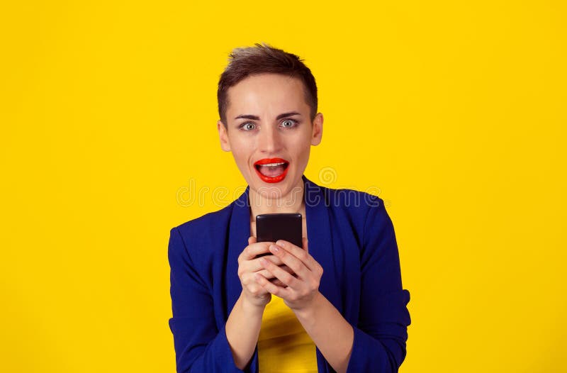 Closeup portrait surprised screaming young girl looking you camera phone in hands seeing news or photos with funny emotion on her face isolated yellow background. Human emotion, reaction, expression. Closeup portrait surprised screaming young girl looking you camera phone in hands seeing news or photos with funny emotion on her face isolated yellow background. Human emotion, reaction, expression