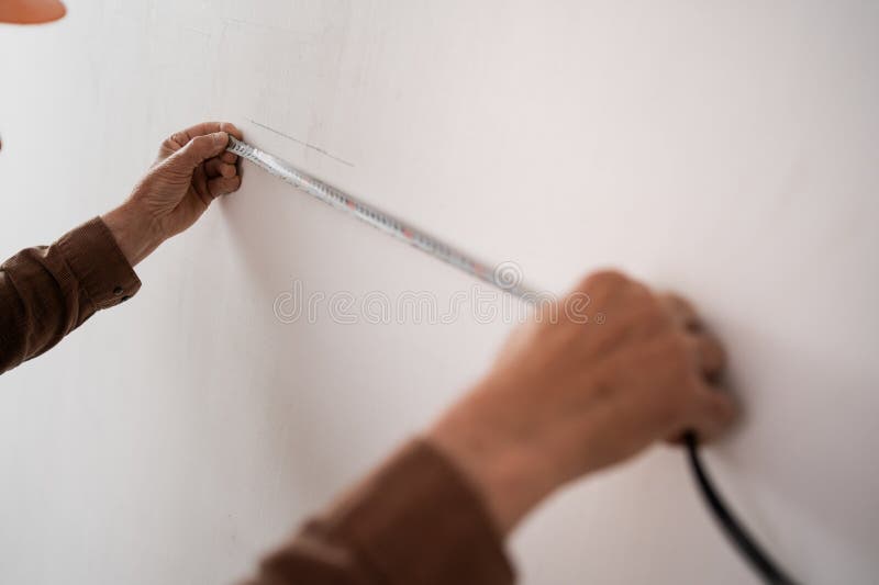 Stängning av äldre byggherhänder som mäter väggar med bandmått. Koncept för renovering och byggnation arkivbild