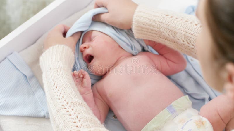 Stängskott av omhändertagande av mor som undertrycker sin lilla 1-månaders gamla babypojke som ligger på bytet av bord. Konceptet arkivfilmer