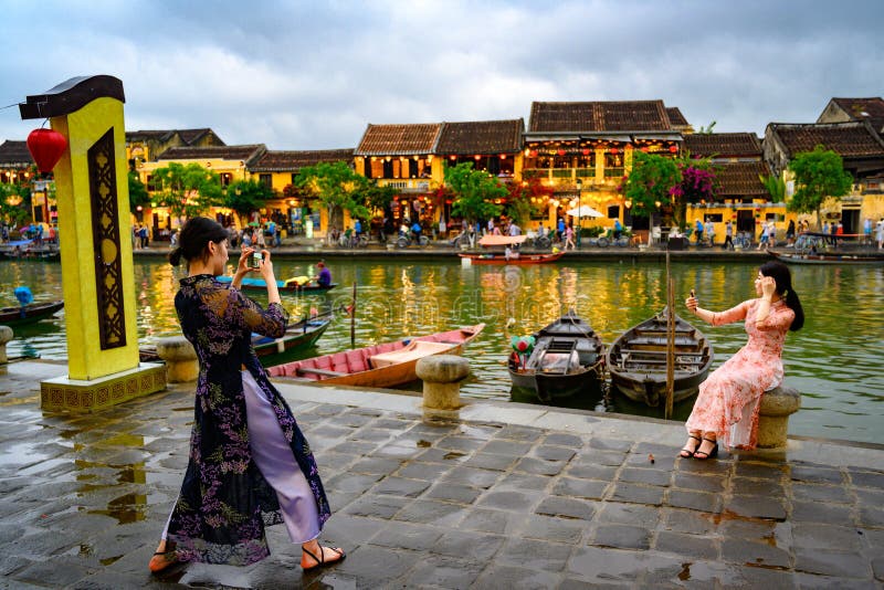St? fr?nsett massturism p? andra sidan av kanalen i den turist- destinationen Hoi An, vietnamesiska kvinnor i Hoi An, Vietnam royaltyfria foton St? fr?nsett massturism p? andra sidan av kanalen i den turist- destinationen Hoi An, vietnamesiska kvinnor i Hoi An, Vietnam royaltyfria foton