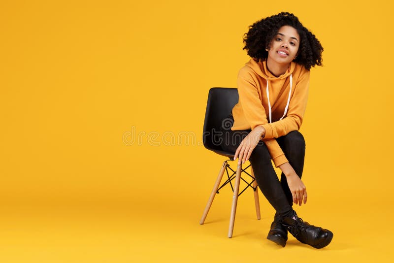 Stående av att charma den unga kvinnan för afrikansk amerikan med iklädd tillfällig kläder för härligt leende som sitter på det s royaltyfri fotografi Stående av att charma den unga kvinnan för afrikansk amerikan med iklädd tillfällig kläder för härligt leende som sitter på det s royaltyfri fotografi