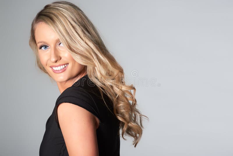 Stående av att le den blonda modellen, på grå bakgrund arkivbilder Stående av att le den blonda modellen, på grå bakgrund arkivbilder