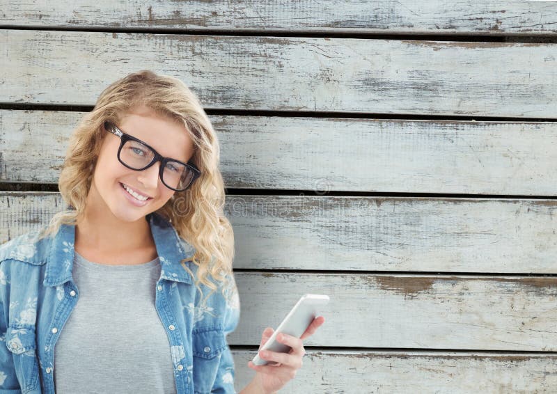 Stående av att le den smarta telefonen för kvinnainnehav mot träväggen arkivfoto Stående av att le den smarta telefonen för kvinnainnehav mot träväggen arkivfoto
