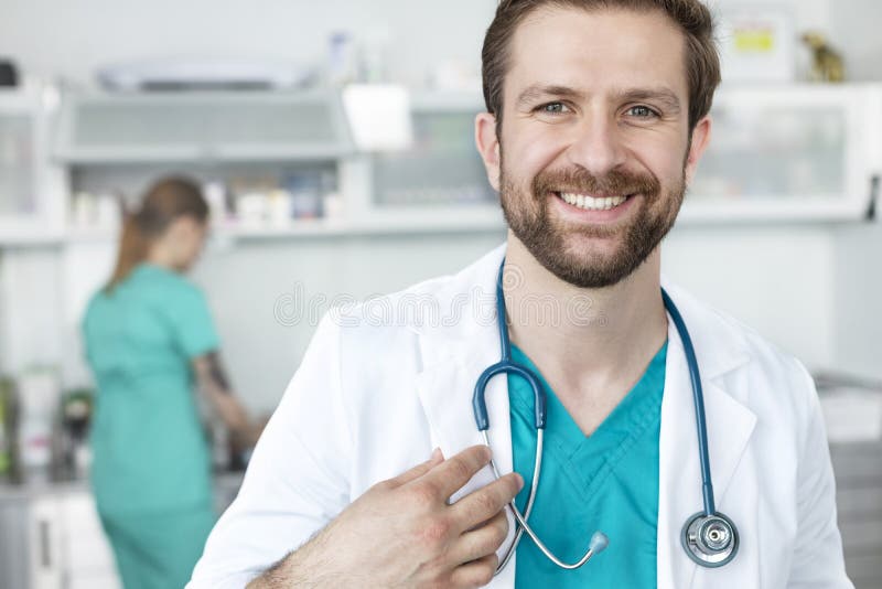 Stående av att le doktorn som står mot coworker på den veterinär- kliniken fotografering för bildbyråer Stående av att le doktorn som står mot coworker på den veterinär- kliniken fotografering för bildbyråer