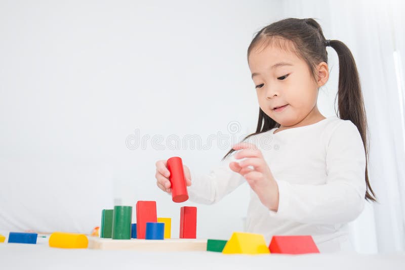 Stående av den asiatiska lilla gulliga flickan som spelar färgrika kvarter på vit bakgrund royaltyfri foto