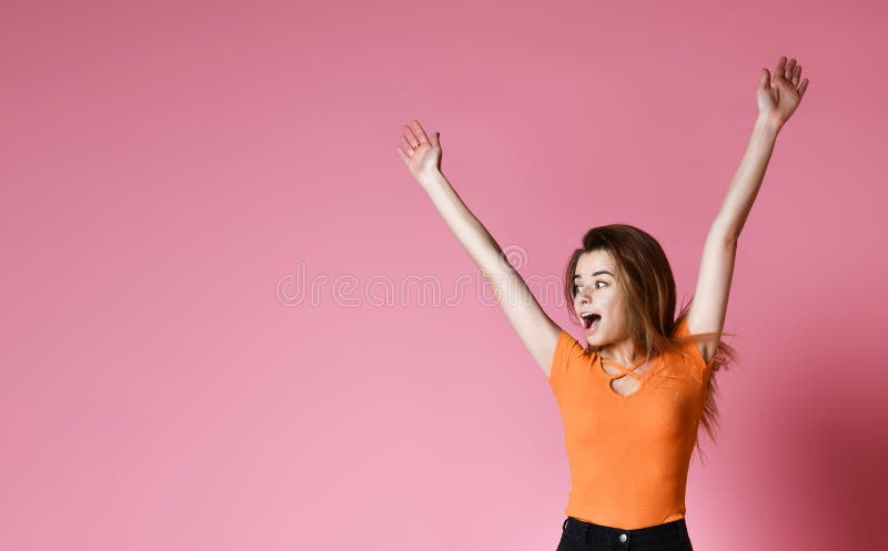 Stående av den gladlynta positiva flickan som hoppar i luften som bort ser kameran som isoleras på rosa bakgrund arkivfoto Stående av den gladlynta positiva flickan som hoppar i luften som bort ser kameran som isoleras på rosa bakgrund arkivfoto